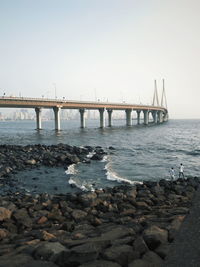 Bridge over calm sea against clear sky