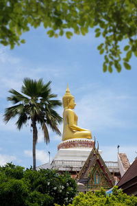 Low angle view of statue amidst trees against sky