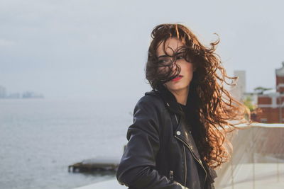 Portrait of smiling young woman standing against sky