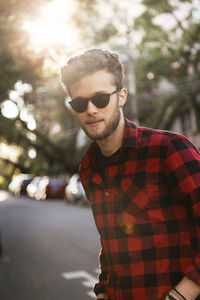 Man wearing plaid shirt and sunglasses while standing on road