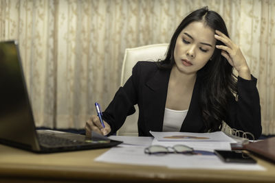 Young woman using mobile phone while sitting on table