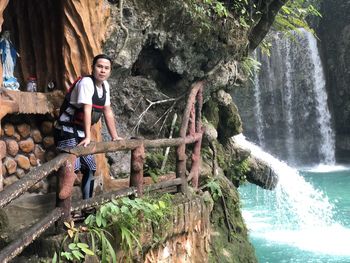 Full length portrait of man standing by railing against waterfall