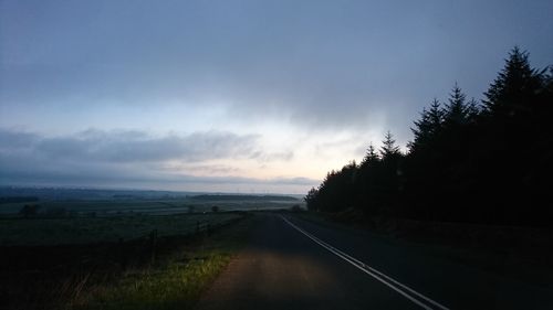 Empty road along countryside landscape at sunset