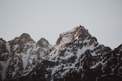 Low angle view of snowcapped mountains against clear sky