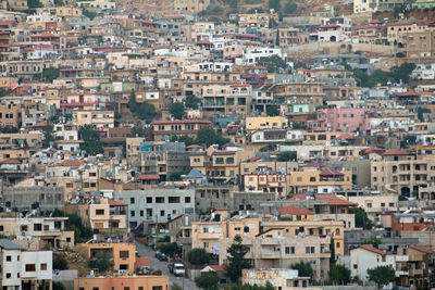 An intricate view of a densely packed town situated on a slope with mountainous backdrop. 