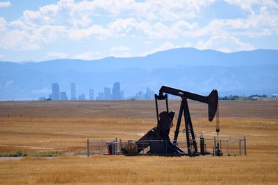 Oil pump on field against mountains