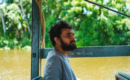 Side view of young man sitting on railing