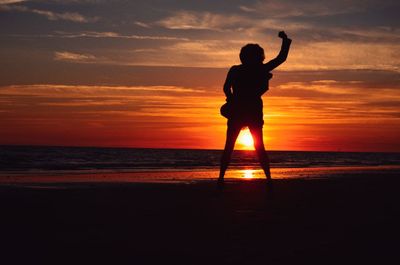 Silhouette of man standing on beach during sunset