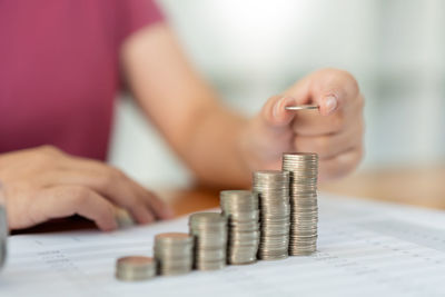 Saving concept the woman piling her coins to make the towers in different heights.