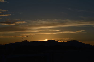 Silhouette birds flying against sky during sunset