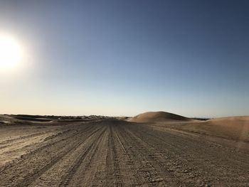 Scenic view of dirt road against clear sky