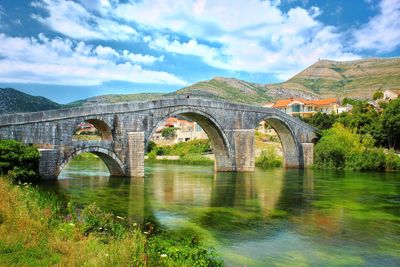 Arch bridge over river against sky