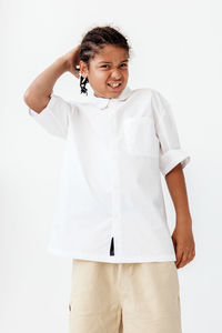 Portrait of young woman standing against white background
