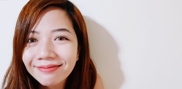 Close-up portrait of a smiling young woman over white background