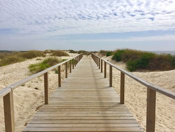 View of wooden footpath leading towards beach