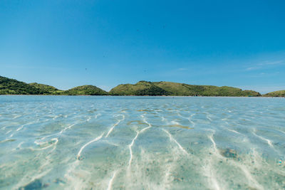 Surface level of sea against clear blue sky