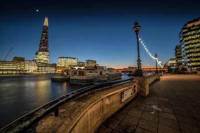 Illuminated shard london bridge by thames river against sky at night