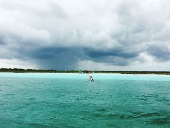 Scenic view of sea with woman rowing boat against sky