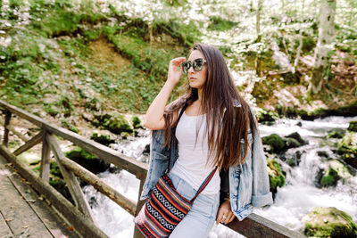 Portrait of young woman wearing sunglasses standing outdoors