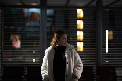 Young woman standing in city during winter at night