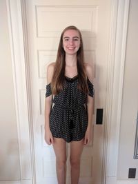 Portrait of smiling young woman standing against door at home