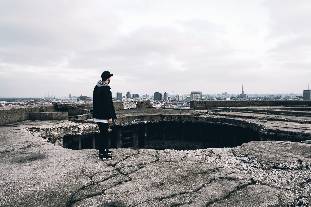 architecture, building exterior, built structure, water, sky, lifestyles, full length, city, leisure activity, standing, rear view, casual clothing, cityscape, cloud - sky, river, men, sea, city life