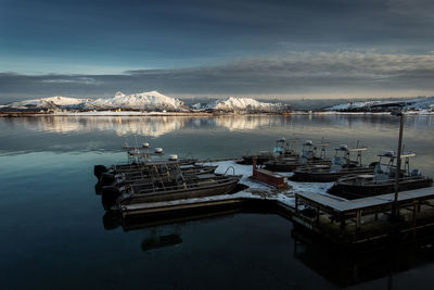 Boats moored at harbor against sky during winter