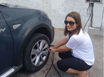 Portrait of smiling woman inflating car tire using air pump