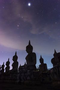 Low angle view of statue against buildings at night