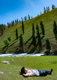 Low section of woman sitting on field against sky