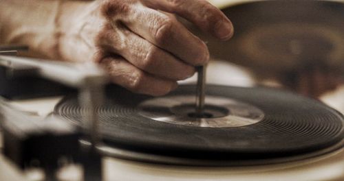 Cropped hand of man on record player needle