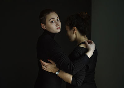 Young couple kissing against black background