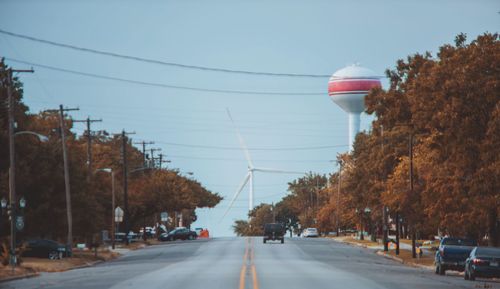 Cars on road by trees against clear sky