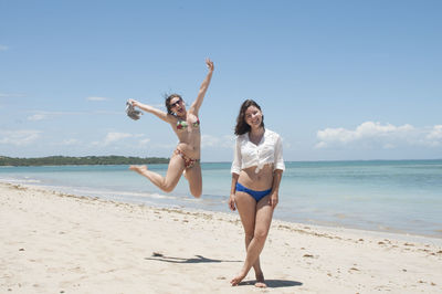 Full length of young woman at beach against sky