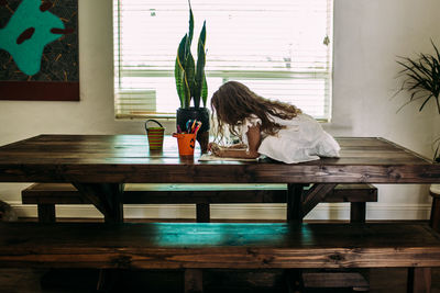 Young girl sitting on top of table coloring