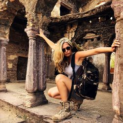 Full length of woman crouching at historic building 