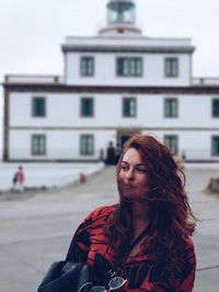 Portrait of young woman standing against lighthouse