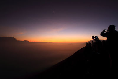 Silhouette people photographing against clear sky during sunset