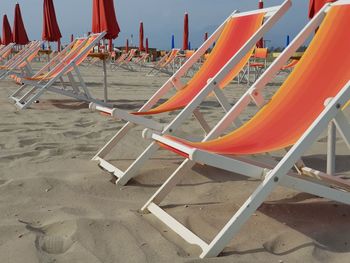 Empty chairs on beach against sea