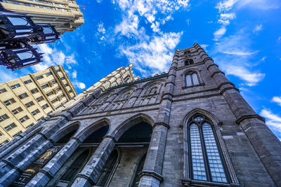 Low angle view of clock tower amidst buildings in city against sky