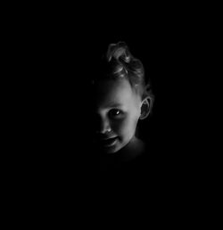 Close-up portrait of a young woman over black background