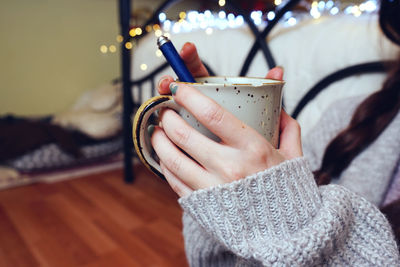 Close-up of hand holding coffee cup at home