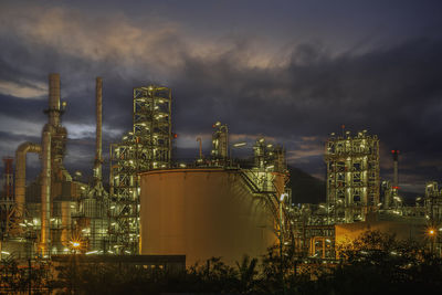 Illuminated factory against sky at night