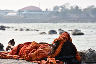 Rear view of people relaxing on rock at beach