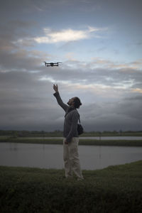 Full length of man standing by airplane against sky during sunset