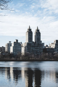 Buildings by lake against sky in city in central park