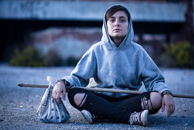 Portrait of young man sitting on road