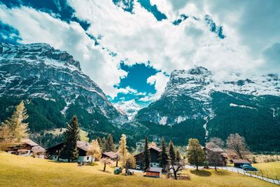 Panoramic shot of people on field by mountains against sky