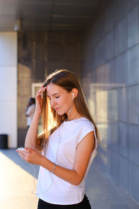 Young woman standing against wall