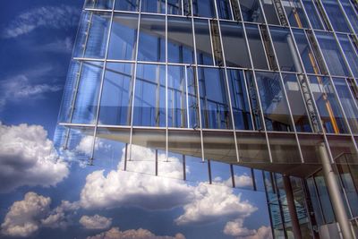 Low angle view of modern building against cloudy sky